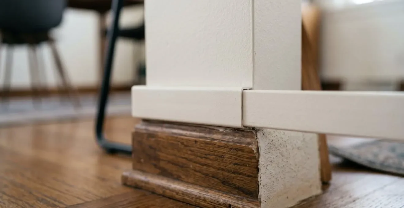 Détail d'un câble électrique sécurisé le long d'une plinthe murale avec goulotte discrète dans un intérieur moderne